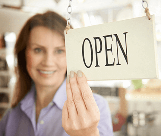 women smiling at open sign